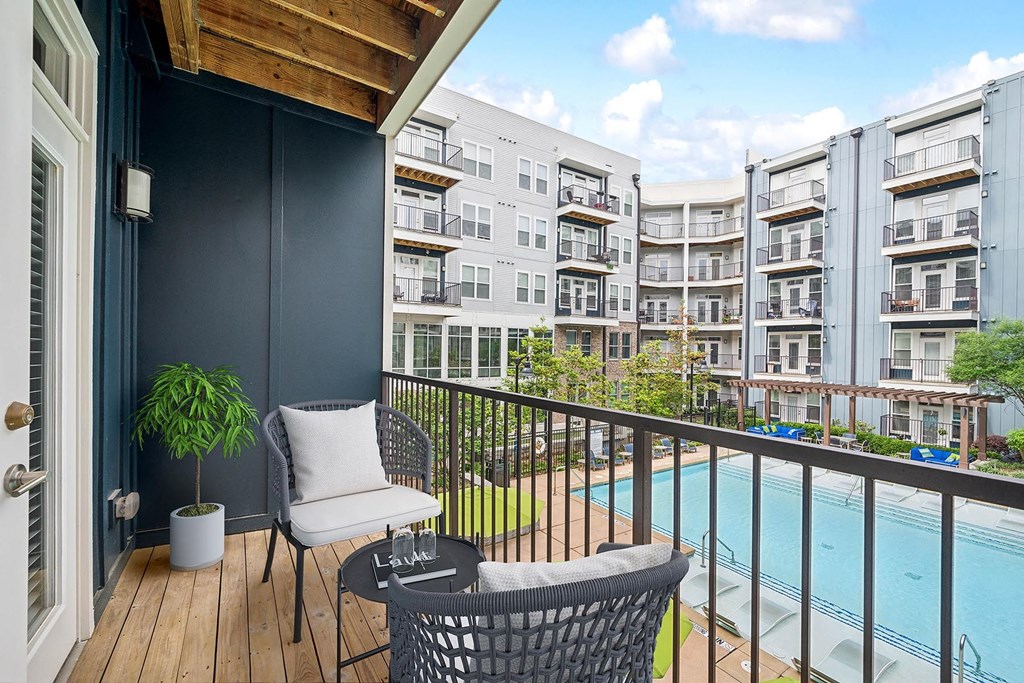 a balcony with chairs and a pool and an apartment building a balcony with chairs and a pool and an apartment building at Glenwood at Grant Park Apartments, Georgia