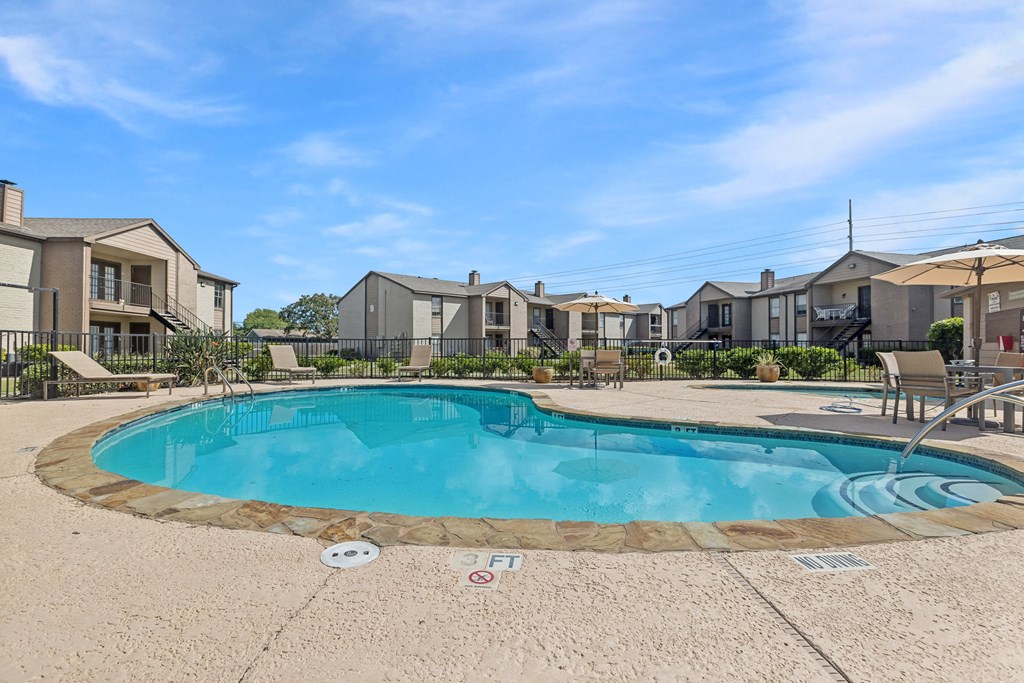 A swimming pool surrounded by a concrete floor and a fence.