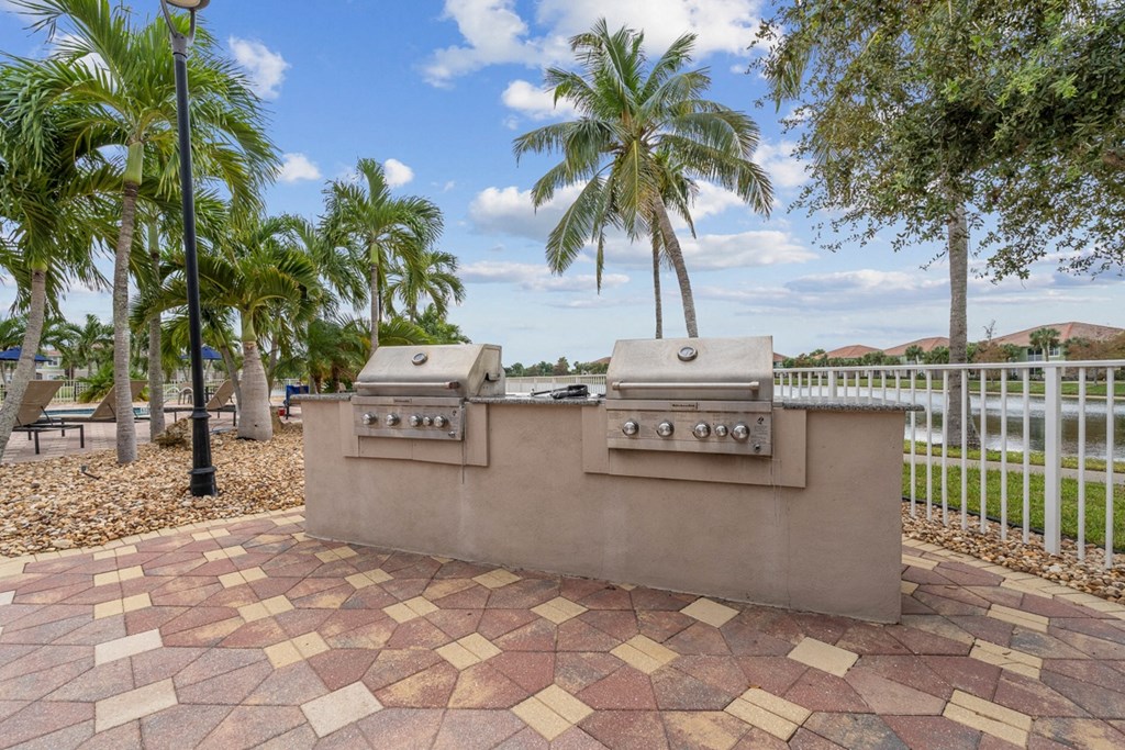 an outdoor kitchen with two gas grills and palm trees at Bay Breeze Villas, Fort Myers, FL