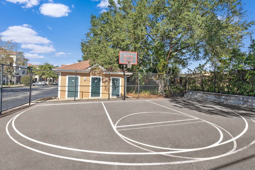 a basketball court in front of a brick building with a tree at Grandeville on Saxon, Orange City, Florida
