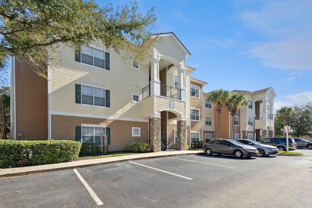 an apartment building with cars parked in a parking lot at Grandeville on Saxon, Orange City
