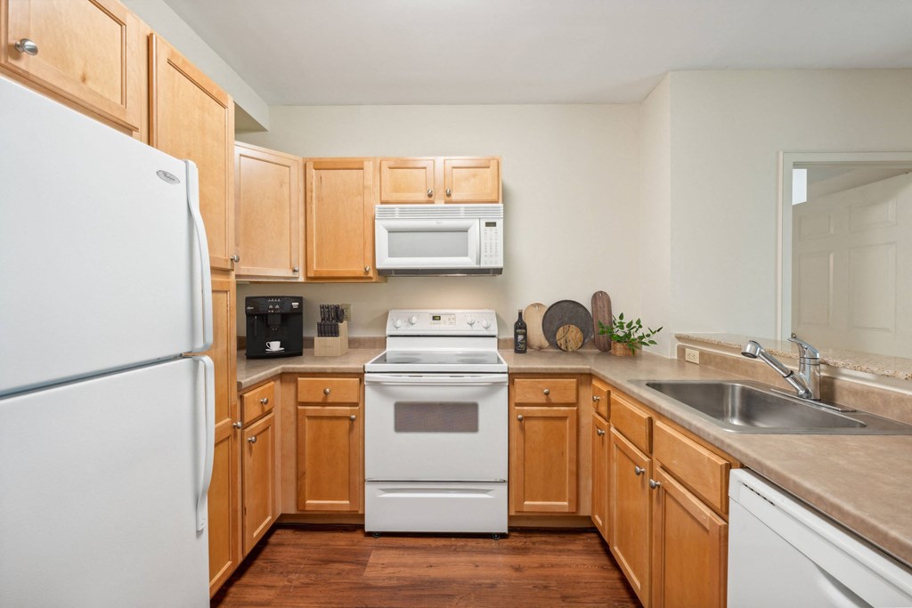 a kitchen with wooden cabinets and a white stove and refrigerator at the Residences at Manchester Place in Manchester, New Hampshire