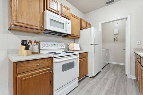 a kitchen with white appliances and wooden cabinets at Grandeville on Saxon, Florida