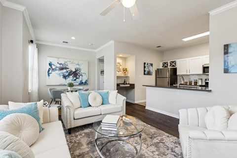 A modern living room with white furniture and a large painting on the wall.