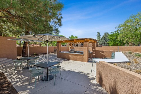 a patio with tables and umbrellas and a jacuzzi at Acacia Gardens, New Mexico