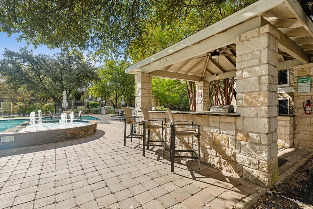 A pool area with a stone patio and a stone building.