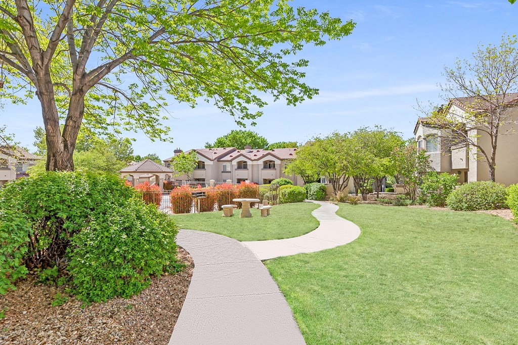 a walkway through a garden with houses in the background