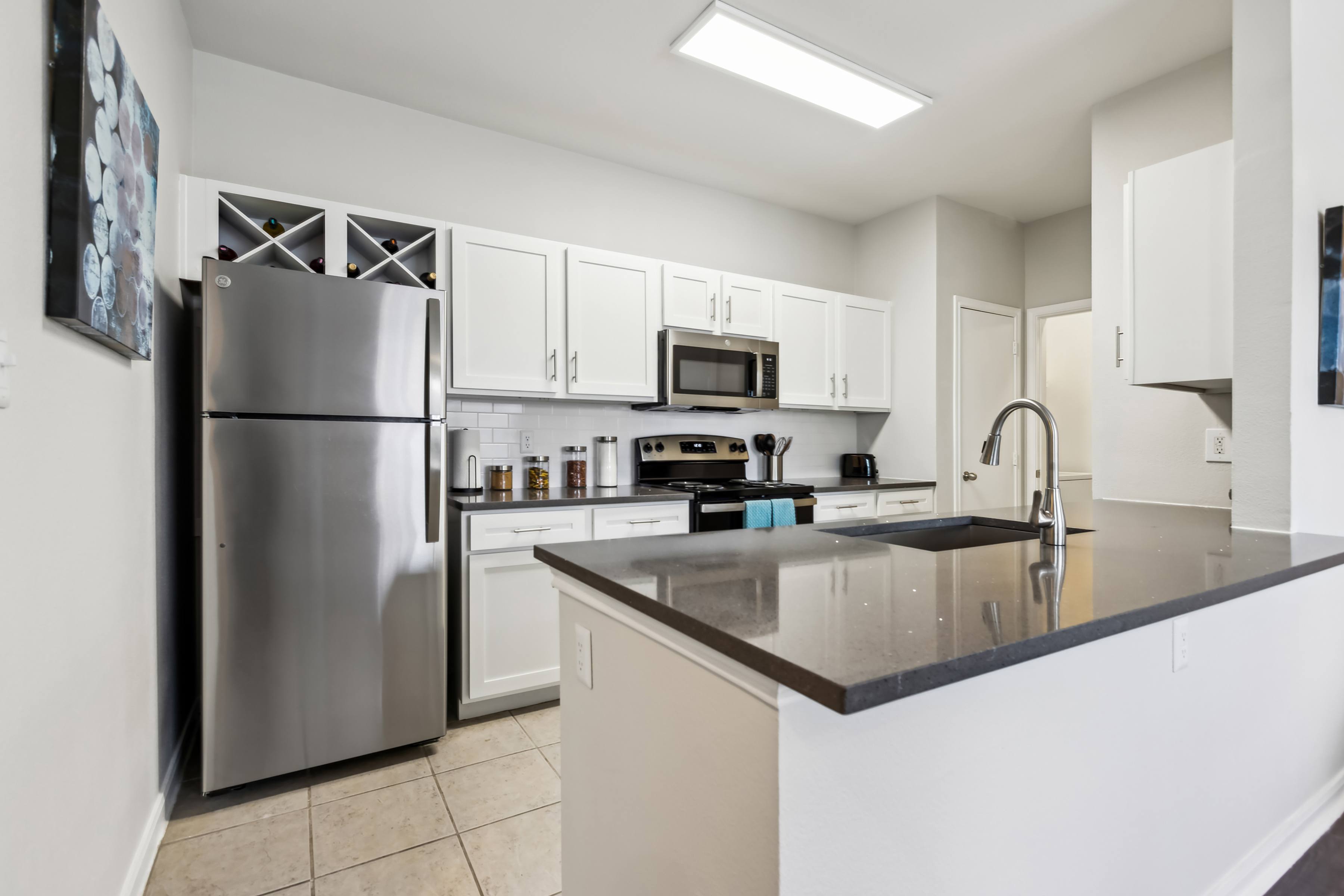 A modern kitchen with a stainless steel refrigerator and white cabinets.