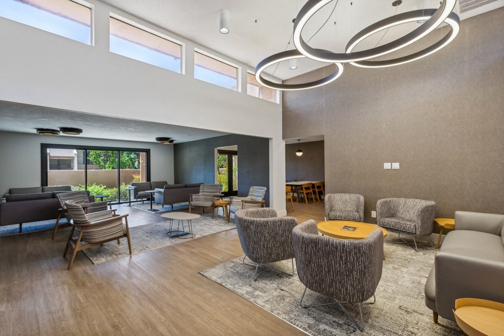 a large living room with chairs and tables and a large window at Acacia Gardens, Albuquerque, NM, 87111