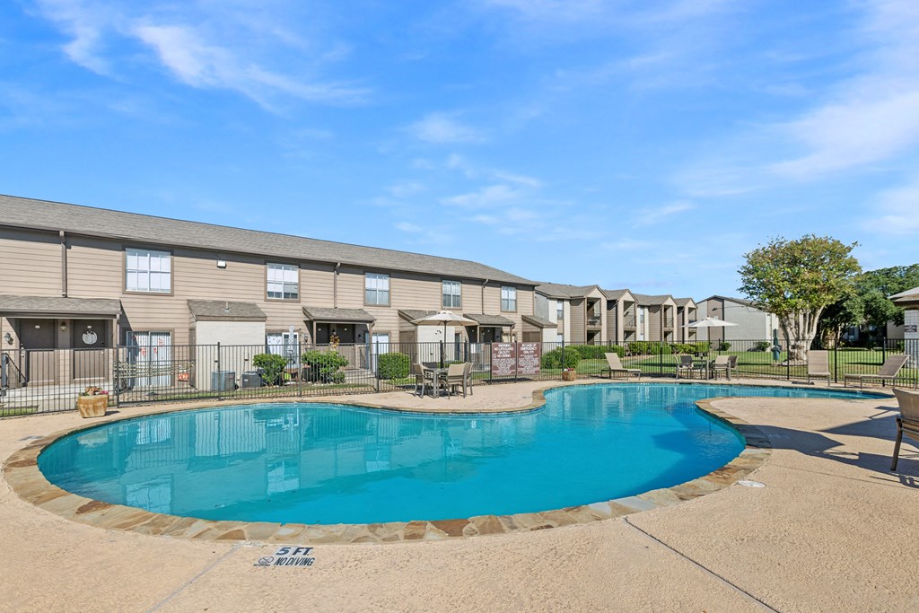 A swimming pool in front of a building with a clear blue sky.