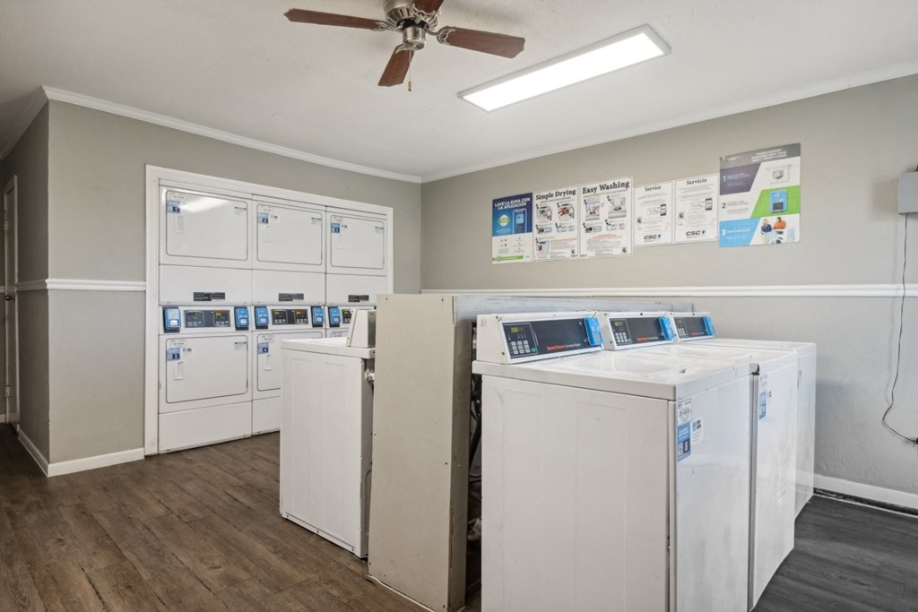 A room with a white ceiling fan and a wall with a poster of a washing machine.