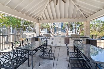 an outdoor patio with tables and chairs and grills
