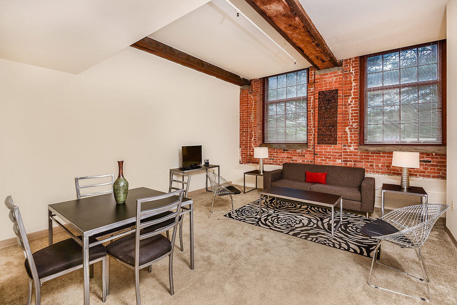 a living room with a table and chairs and a brick wall
