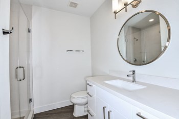 renovated home | bathroom with white cabinets, round mirror, shower stall - Photo Gallery 4