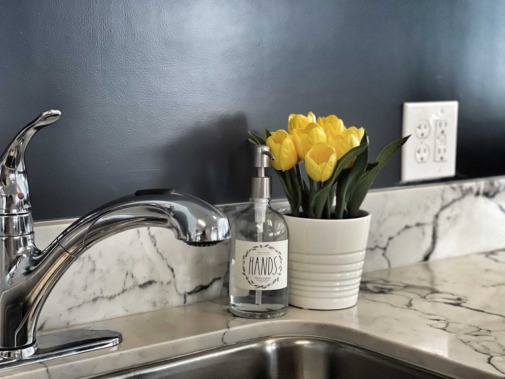 a kitchen sink with a vase of yellow flowers next to it at 2300 West Apartments, Reno, NV