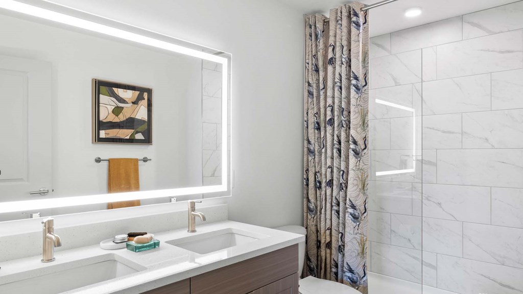 A bathroom with a marble wall and a floral shower curtain. at Lucie at Tradition Apartments, Port St. Lucie