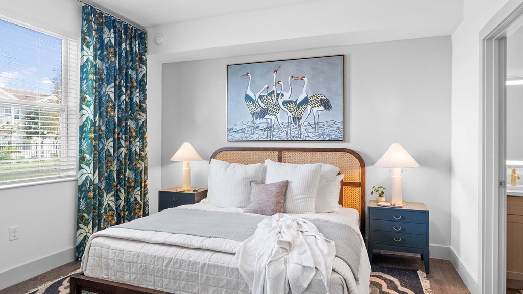 A bedroom with a large bed and a painting of two birds on the wall. at Lucie at Tradition Apartments, Florida, 34987