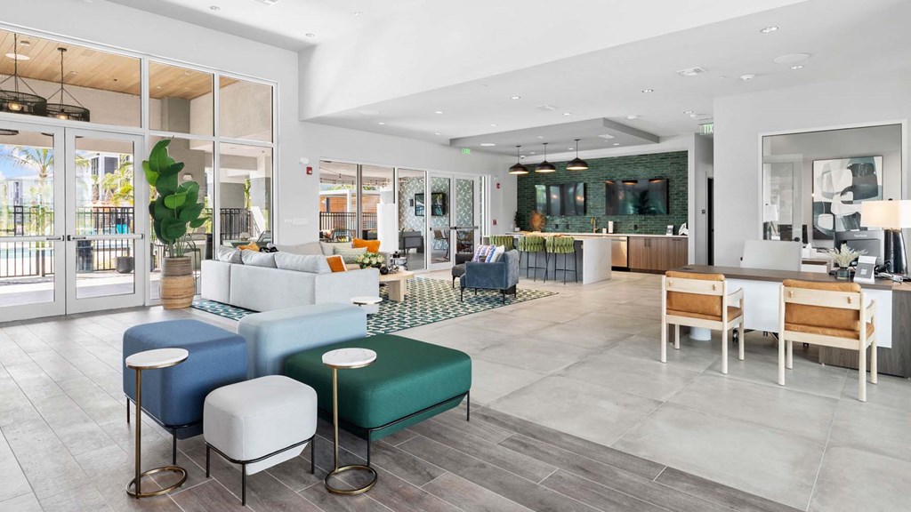A modern living room with a white sofa, a green ottoman, and a wooden coffee table. at Lucie at Tradition Apartments, Port St. Lucie, FL