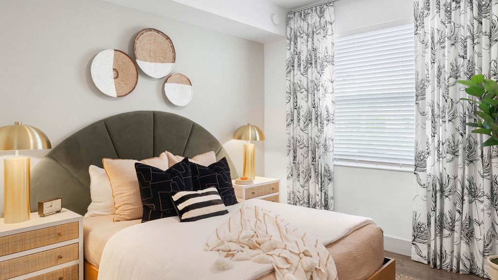 A bedroom with a large bed, a headboard, and a plant. at Lucie at Tradition Apartments, Florida