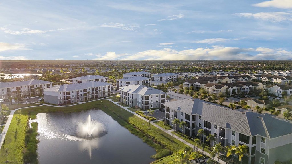 A large building complex with a fountain in the middle of a pond. at Lucie at Tradition Apartments, Port St. Lucie