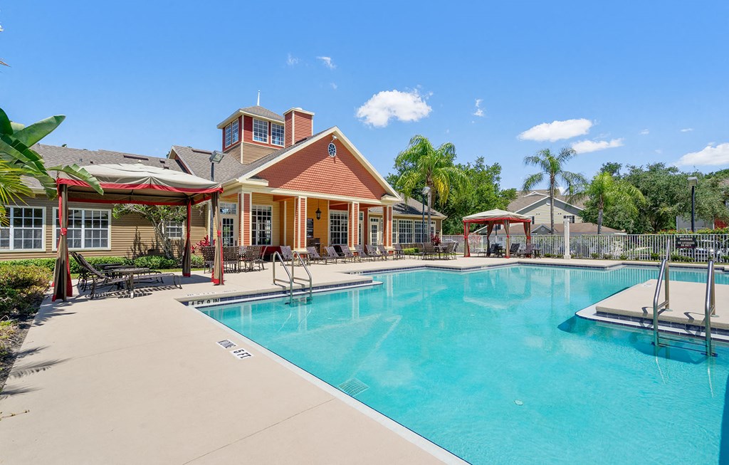 a pool with chairs and umbrellas in front of a building at Bella Vista on Park, Florida, 33563