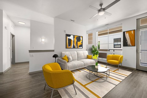 A modern living room with a grey sofa, yellow chairs and a painting on the wall.