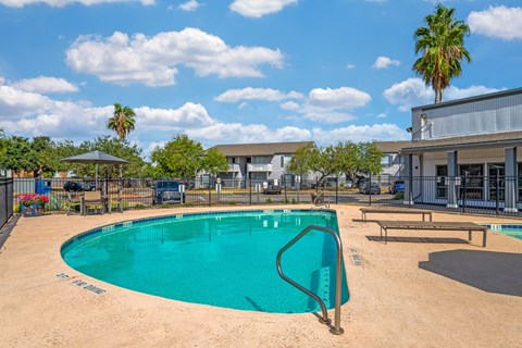 A swimming pool surrounded by a fence and a playground.