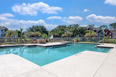A swimming pool surrounded by a concrete deck and a residential area in the background.