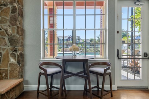 A dining room with a table and chairs in front of a large window.