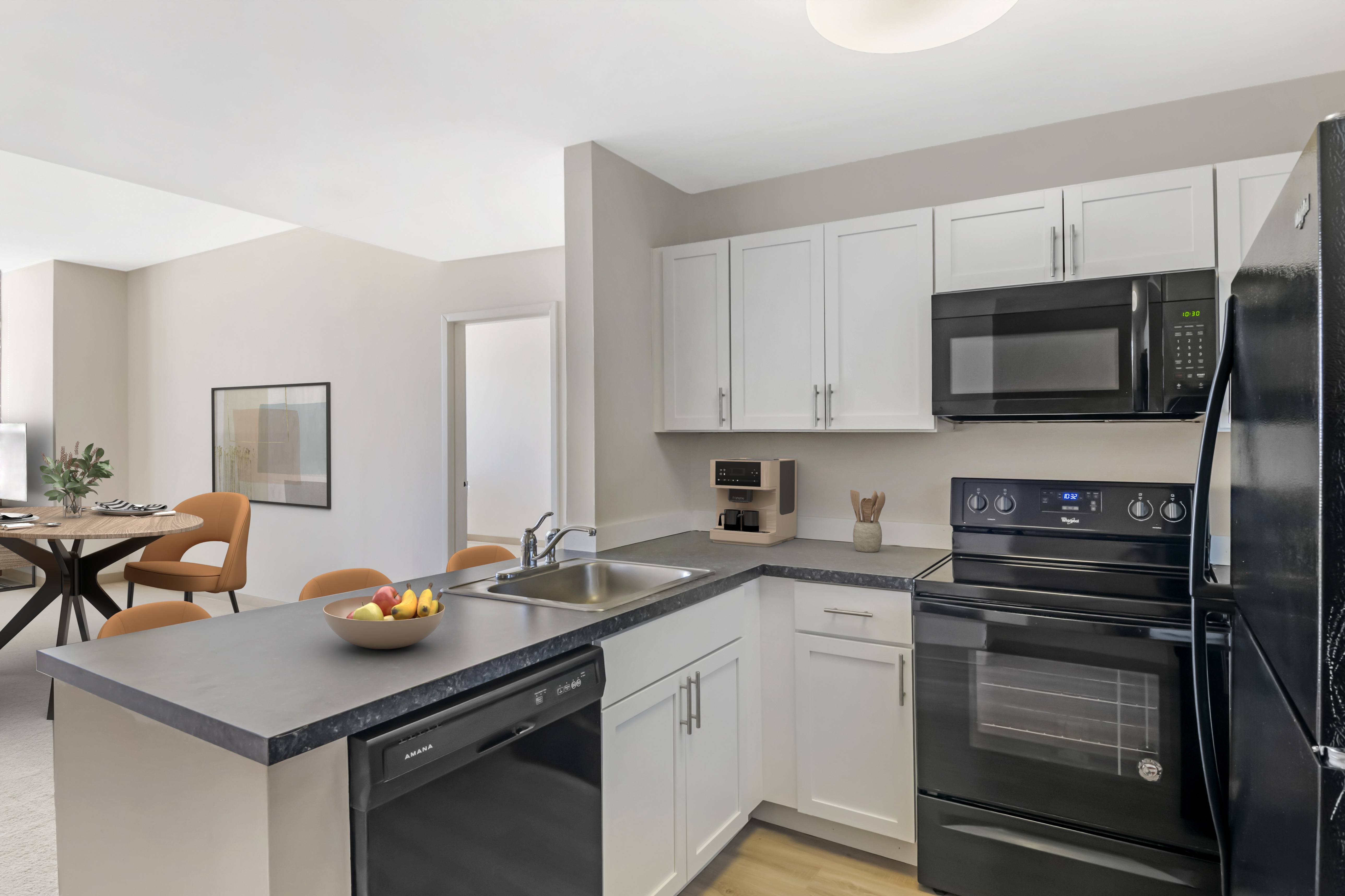 A modern kitchen with black appliances and white cabinets.