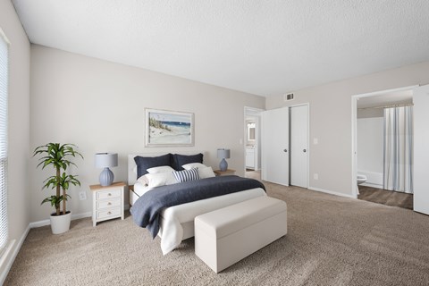 A bedroom with a bed, nightstand, and a plant.