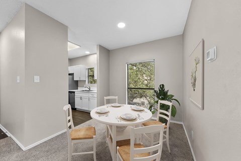 A dining room with a table set for two and a view of the backyard.
