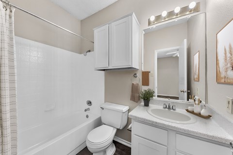 A white bathroom with a toilet, sink, and a shower.