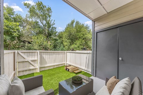 A patio with a table and chairs overlooking a fenced-in yard.