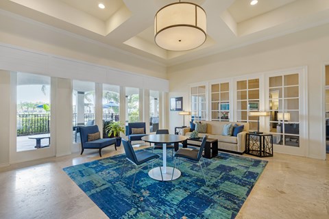 A spacious living room with a blue rug and a large window.