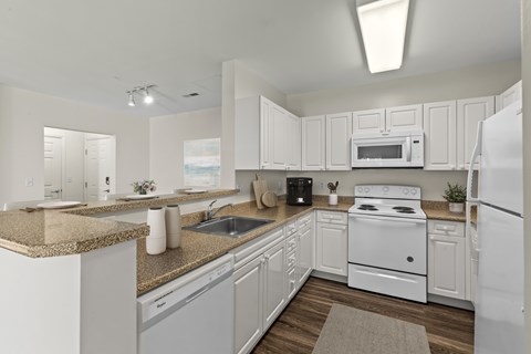 A white kitchen with a stove, microwave, and refrigerator.