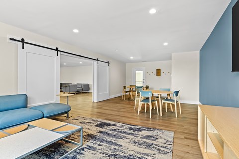 A living room with a blue couch and a rug.