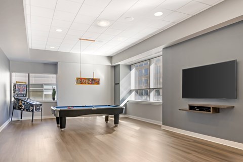 A room with a pool table and a television.