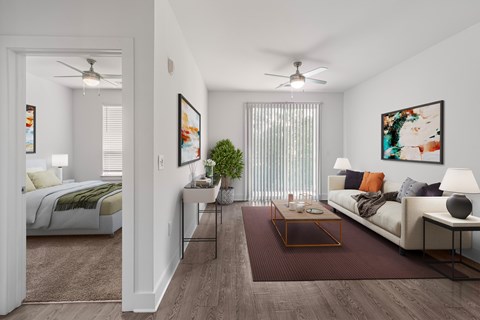 A modern living room with a white sofa, a coffee table, and a bed with a green blanket.