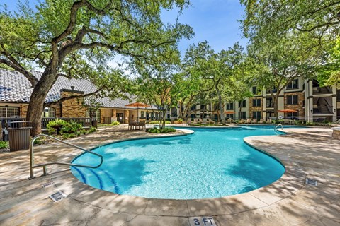 A swimming pool surrounded by trees and buildings.
