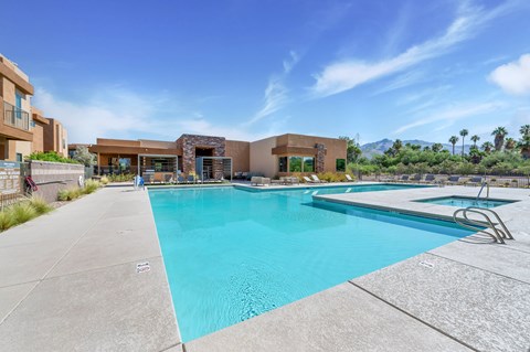 A large swimming pool with a diving board and a building in the background.