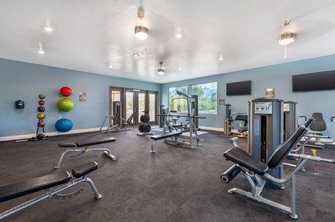 A gym with a variety of equipment including weights and exercise machines.