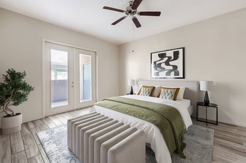 A bedroom with a bed, pillows, a ceiling fan, and a plant.