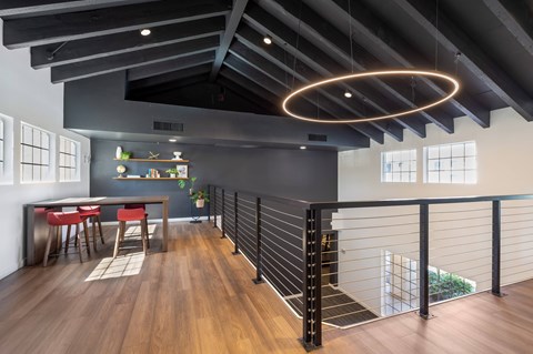 A modern dining area with a black railing and a wooden floor.