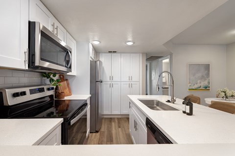 A modern kitchen with white cabinets and a black stove top.