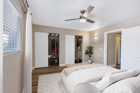 A bedroom with a bed, a ceiling fan, and a window with blinds.