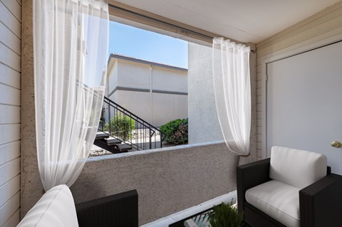 A balcony with a chair and a table with a plant on it.
