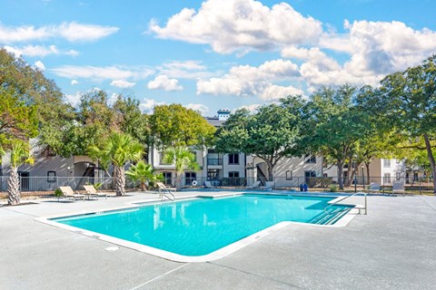 A swimming pool surrounded by trees and buildings.