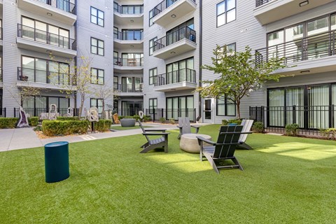 A modern apartment complex with a green lawn and outdoor furniture.