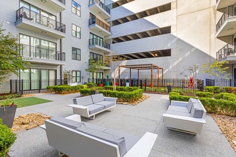 A modern outdoor seating area with grey couches and a black fence.